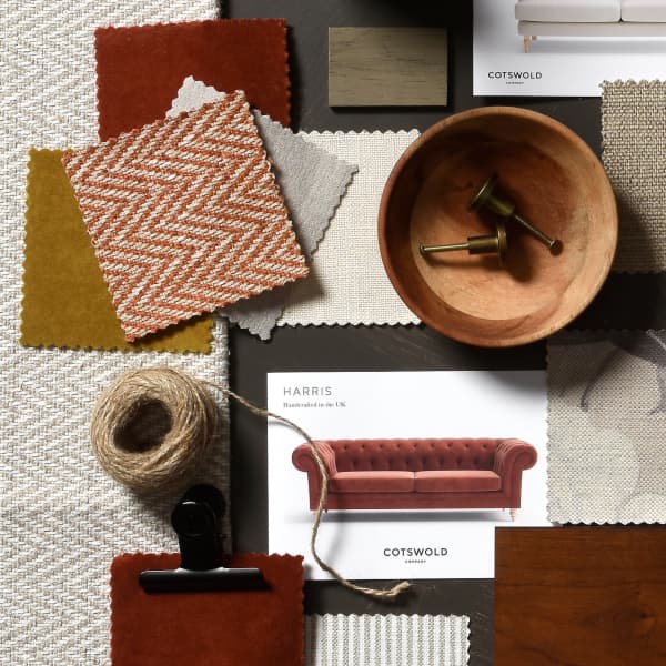 A flatlay of fabric swatches, a wooden bowl with handles, twine, and a furniture catalogue featuring a red sofa.
